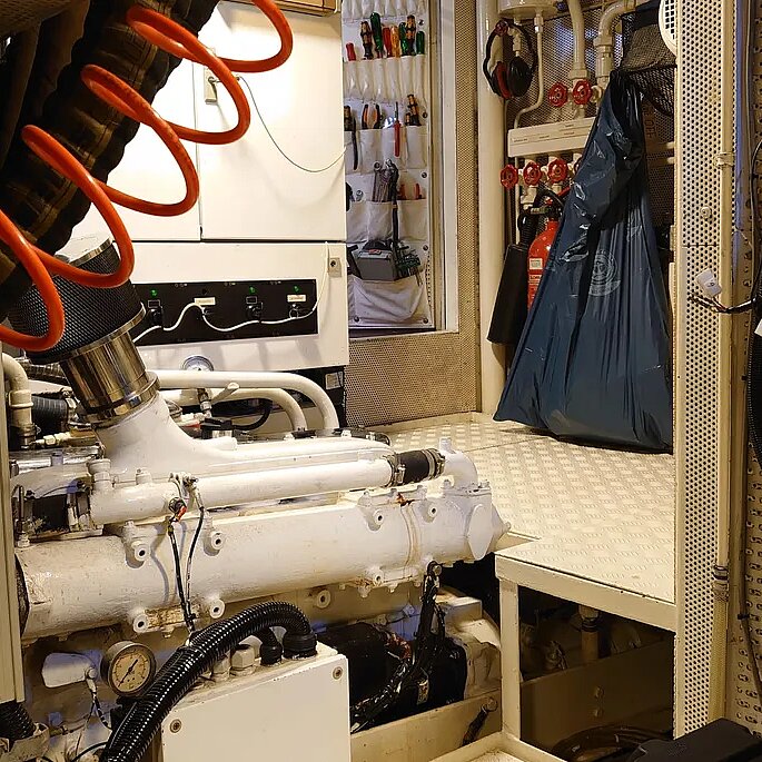Bild von Innen zur Tür des Maschineraums. man sieht Motor und Druckschlauch